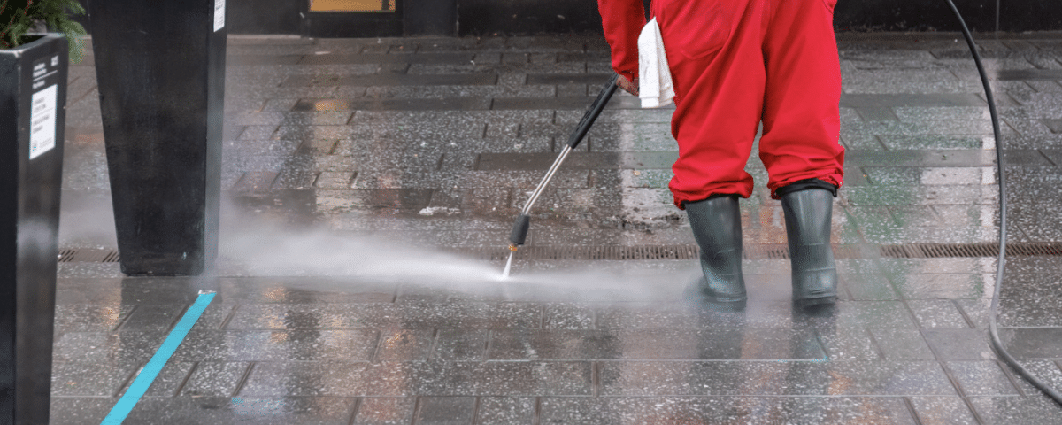 person power washing stone walkway of business