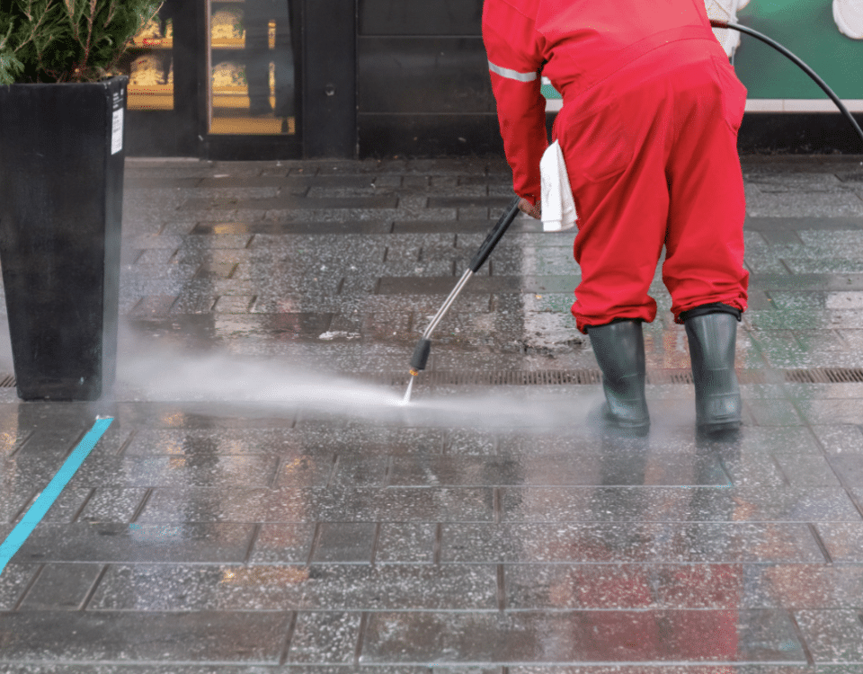 person power washing stone walkway of business